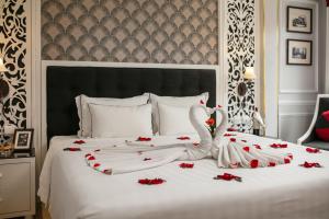 a white bed with red rose petals on it at Lavender Central Hotel & Spa Hanoi in Hanoi +37 photos