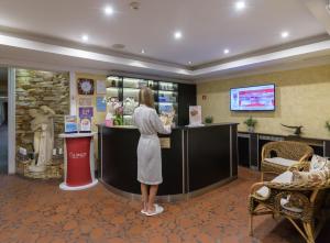 a woman standing at a counter in a hotel lobby at SPA Club Bor Hotel in Velingrad