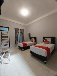 1 dormitorio con 2 camas y mesa. en Dnaiko Syariah Hotel en Bukittinggi
