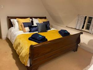 uma cama com cobertor amarelo e almofadas em Beautiful Character Thatched Pet Friendly House em Enford