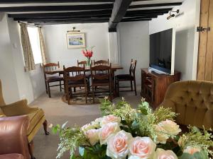 a living room with a table and a television and roses at Beautiful Character Thatched Pet Friendly House in Enford