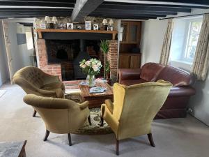 a living room with two chairs and a leather couch at Beautiful Character Thatched Pet Friendly House in Enford