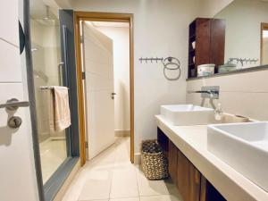リヴィエール・ノワールにあるLuxury Waterfront Apartmentの洗面台2つとシャワー付きのバスルーム