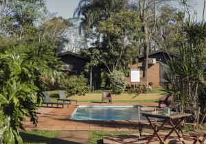 einen Pool mit Stühlen, einen Tisch und ein Haus in der Unterkunft El Descanso Iguazú by DOT Cabana in Puerto Iguazú