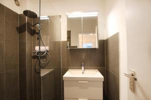 uma casa de banho com um lavatório e um chuveiro com um espelho. em LaMiaCasa Design Apartment near Ludwigsburg 2,5 rooms 75 sqm em Schwieberdingen