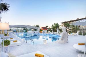 a pool at a resort with white furniture and a building at Augusta Eco Wellness Resort 4 Superior in Sanxenxo