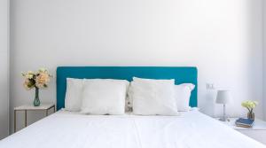 a white bed with a blue headboard and white pillows at Sunlit 1 Bedroom Apt in Porta Nuova in Milan