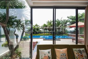 a living room with a view of a pool through windows at Cozrum Luxury - Aria Resort Vũng Tàu in Xa Thang Nhut