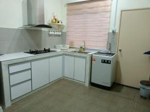 a kitchen with white cabinets and a sink and a stove at ZR D'Chili Homestay, Kemaman in Cukai