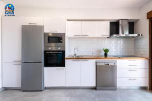una cocina con armarios blancos y electrodomésticos de acero inoxidable en Apartamentos Arcos I Casa Azahar, en Alcossebre