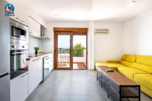 a living room with a yellow couch and a kitchen at Apartamentos Arcos I Casa Azahar in Alcossebre