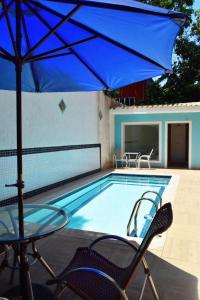 - un parasol bleu et des chaises à côté de la piscine dans l'établissement Flat's Refúgio Vip, à Cabo Frio