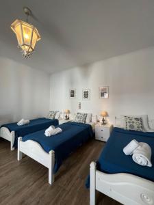 a bedroom with three beds and a chandelier at Katerina Apartments & Studios in Naousa