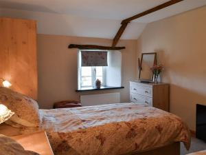sypialnia z łóżkiem z komodą i oknem w obiekcie Knotty Corner Cottage w mieście Abbotsham