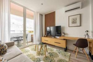 a living room with a couch and a television at Timeless Beach III Apartment in Armação de Pêra
