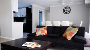 a living room with a black couch and a table at Magic in Medlow in Medlow Bath