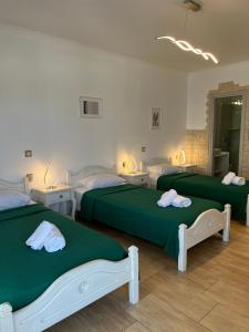 a bedroom with three beds with green sheets at Katerina Apartments & Studios in Naousa