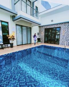 a woman standing in front of a swimming pool at Spring Fields Homestay by Sizma in Semenyih