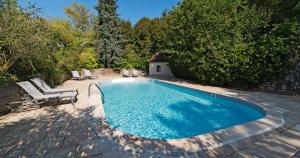 a swimming pool in a yard with two lounge chairs at Le Moulin De Connelles in Connelles