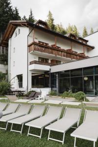 a house in the mountains with lounge chairs in the yard at Hotel Rosengarten in Nova Levante