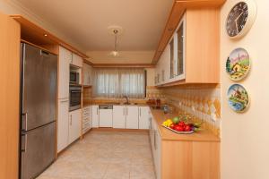 a kitchen with white cabinets and a stainless steel refrigerator at Zante View villa Odysseus in Planos