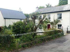 een wit huis met een hek ervoor bij Rural 17th century barn studio apartment in Cheriton Bishop