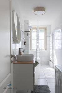 Baño blanco con lavabo y espejo en Stilvolles Apartment im Zentrum mit Netflix WE23 en Magdeburgo