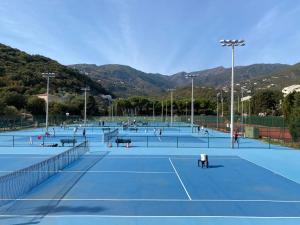 a group of people playing tennis on a tennis court at La Bergerie Fiumicellu in Santa-Maria-di-Lota