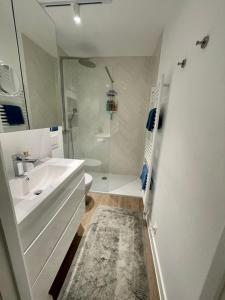 La salle de bains blanche est pourvue d'un lavabo et d'une douche. dans l'établissement Appartement 't Pand, à Nieuport