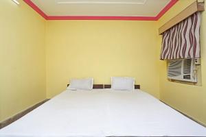 1 dormitorio con 1 cama blanca grande y ventana en OYO Hotel Surya, en Rourkela