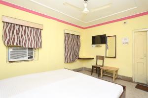 1 dormitorio con 1 cama, TV y silla en OYO Hotel Surya, en Rourkela