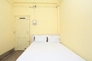 Cama blanca en una habitación pequeña con puerta en OYO Hotel Surya, en Rourkela