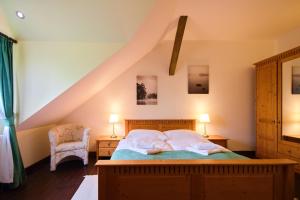 a bedroom with a bed with two lamps and a chair at Hotel Buchlov in Buchlovice