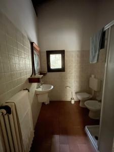baño con 2 aseos, lavamanos y ventana en Agriturismo Mulino in Pietra, en Casina