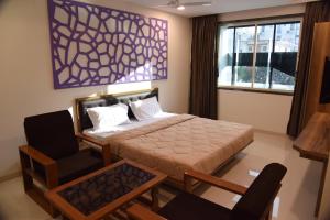 een slaapkamer met een bed, een stoel en een raam bij The Pacific Hotel in Vadodara