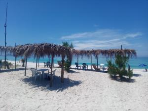 - une plage avec des tables, des chaises et un parasol dans l'établissement POUSADA CAMINHO DAS ÁGUAS, à Arraial do Cabo