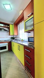 una cucina con armadi gialli e rossi e forno a microonde di Ático punta Umbría a Punta Umbría
