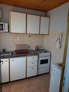 a kitchen with white cabinets and a stove top oven at Los Nopo in Trevelin