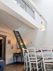 a dining room with white chairs and a staircase at Apartament Old England in Żywiec
