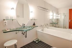 une salle de bain avec un lavabo, une baignoire et un miroir dans l'établissement Villa Medici 10 a, à Ahlbeck