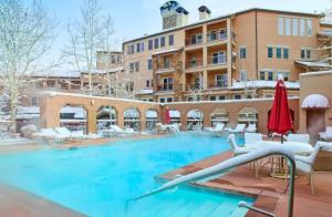 スノーマス・ビレッジにあるSki In, Ski Out, 3 Bedroom Luxury Residence On Fanny Hill In Snowmass Villageの大きなスイミングプール(椅子付)と建物