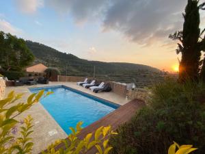 uma villa com uma piscina com um pôr-do-sol em עיינות ספיר - Einot Sapir em Sappir