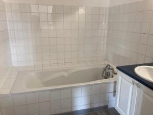 Baño de azulejos blancos con bañera y lavamanos en Le Matadri, en Grane