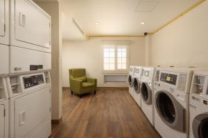 uma lavandaria com máquinas de lavar roupa e uma cadeira verde em Extended Suites Chihuahua La Juventud em Chihuahua