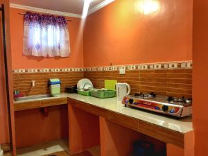 a kitchen with orange walls and a counter top at Cardo Homestay Siargao in General Luna +5 photos