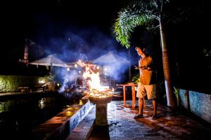 a man standing in front of a fire at night at The Granyam Garden Cottage in Nusa Penida