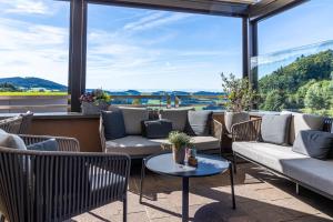 eine Terrasse mit Sofas, Tischen und großen Fenstern in der Unterkunft Landhotel Atzmüller in Waxenberg