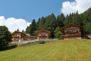 eine Gruppe von Gebäuden auf einem Hügel mit einem Feld in der Unterkunft Residence Kalchgruberhof Fichte in Ulten