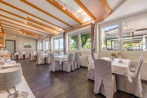 a restaurant with white tables and chairs and windows at Landhotel Atzmüller in Waxenberg