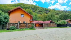 an orange house with a fence in front of a mountain at Casa Ana in Gureni